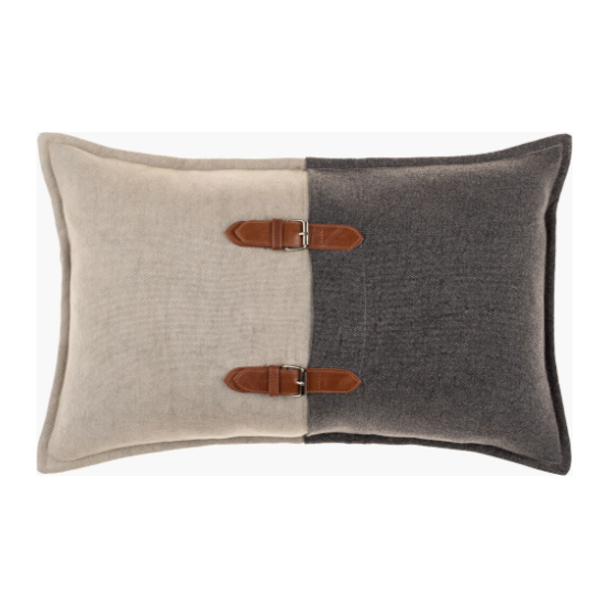 The Buckle Lumbar Throw Pillow features a 14x22 rectangular shape, half beige and half dark gray fabric, accented by two brown leather straps with silver buckles. It includes a feather down insert, soft texture, and piped edges for a refined look.