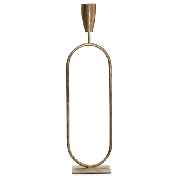 The Trumpet Candle Holder - Short is a tall, oval-shaped brass candlestick with a minimalist design and exquisite handcrafted detail. It features an elongated frame with a candle holder atop and a flat rectangular base for support, all in polished, shiny brass.