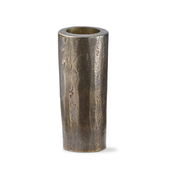 The Hammered Tall Taper Holder is a tall, cylindrical vase made of dark, textured metal with a rustic, uneven surface that highlights its hand-forged iron construction. It features a slightly tapered shape and wide opening and stands on a plain white background, casting a subtle shadow.
