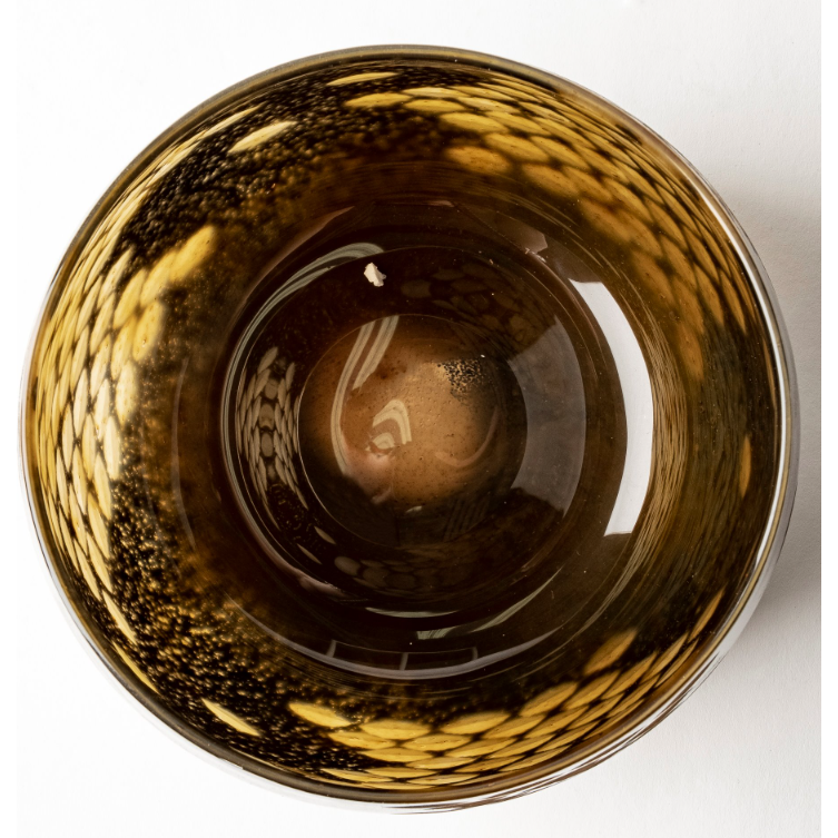 From a top-down perspective, the Marina Black and Gold Glass Vase showcases its glossy brown interior complemented by a textured outer rim. This sophisticated design is adorned with shimmering golden scales, reminiscent of black with gold details, forming an intricate and reflective pattern. The smoothness at the center provides a striking contrast to the textured perimeter.