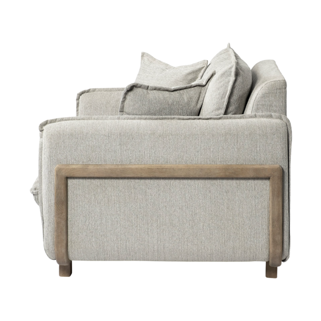 The Veyra Plush Upholstered Armchair in Frost Grey exudes sophisticated comfort with its boxy design, plush cushions, and exposed wooden base and armrests. Its two accent cushions enhance the chair's modern luxury against a plain white background.