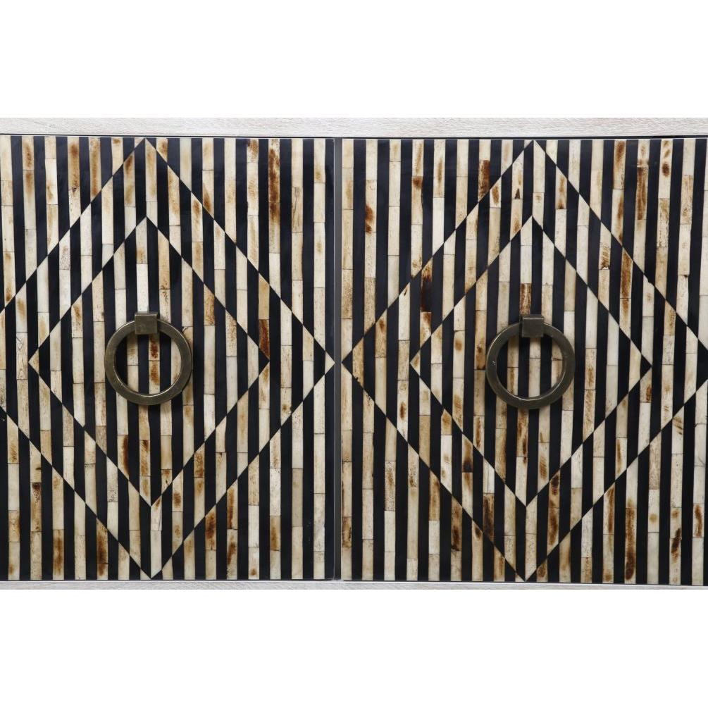 The Terra Noir Sideboard Media Cabinet showcases a geometric pattern with vertical black and white stripes and brown accents. Two central diamond shapes surround round, bronze-colored metal handles on the horn and mango wood piece, creating a striking optical illusion.