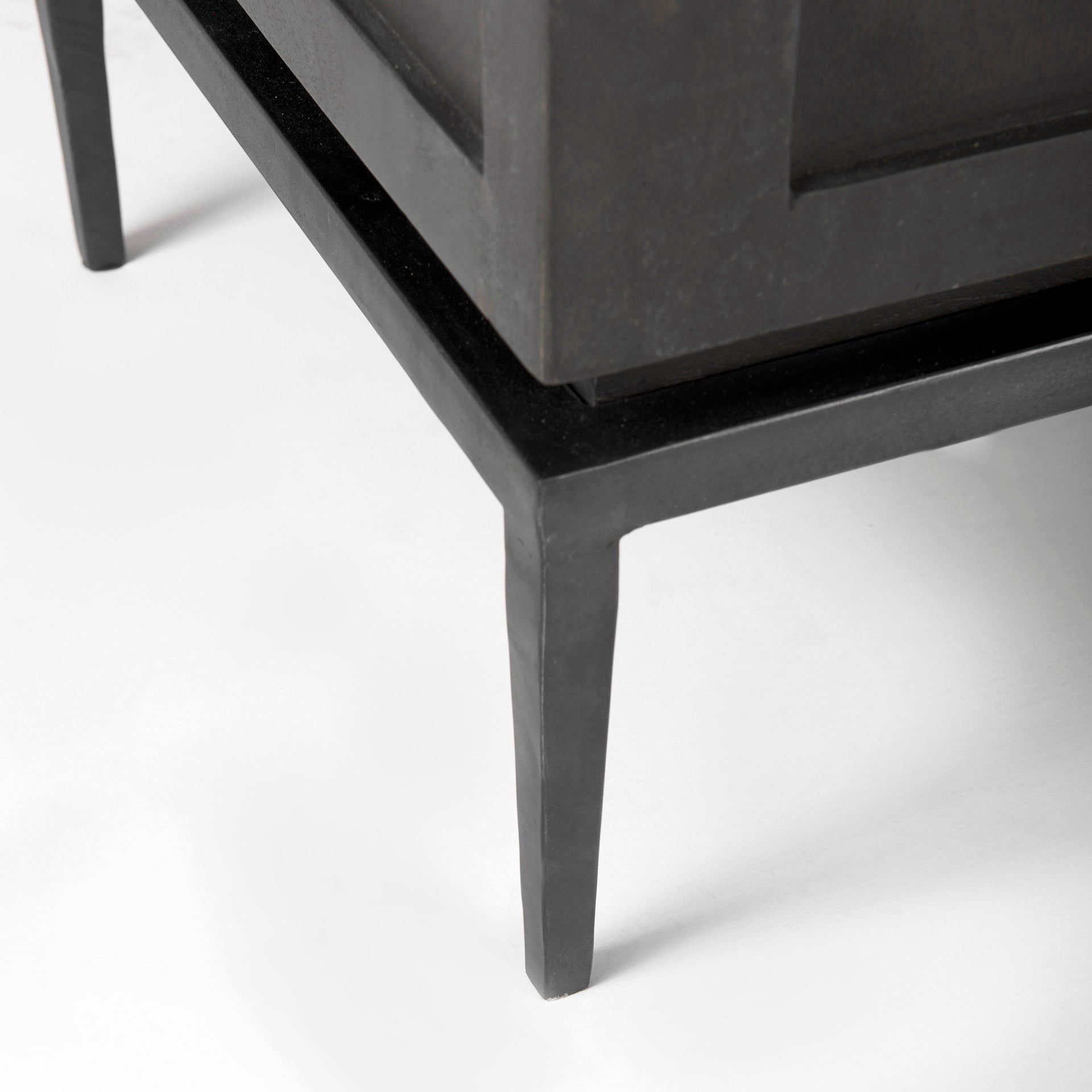 Close-up of a black metal cabinet leg on a white background