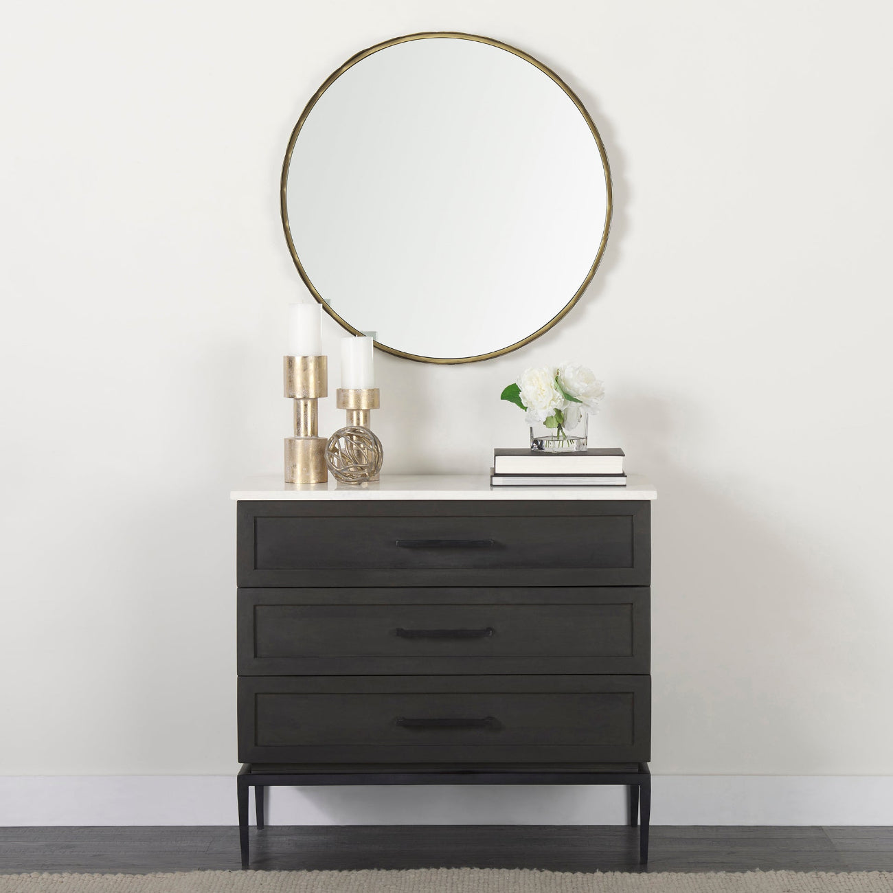 Black dresser with a round mirror above it against a white wall.