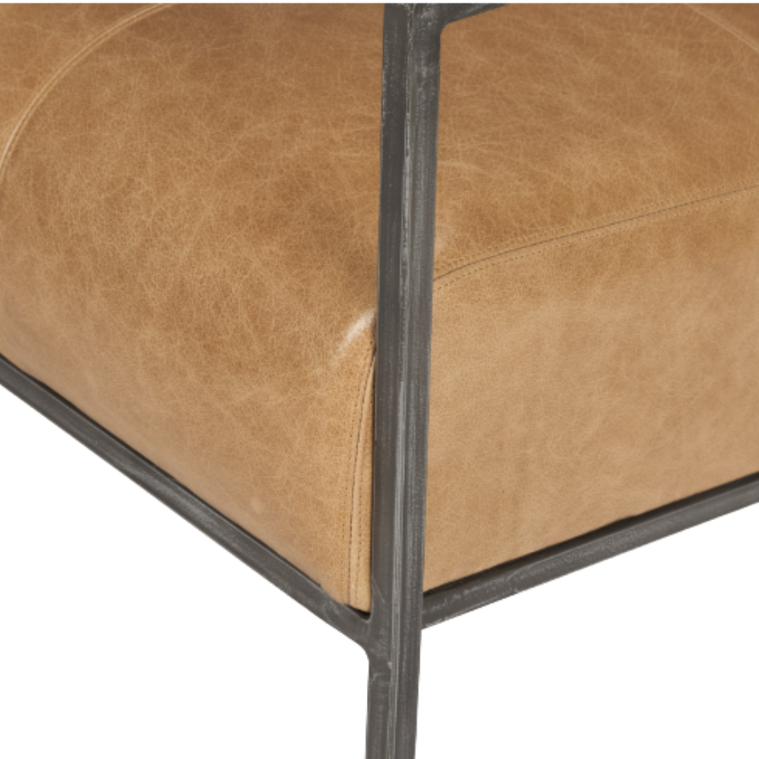 Close-up of a brown leather cushion with a smooth, slightly worn texture and visible stitching, set in a squared black metal frame for a modern touch to the Vercelli Handcrafted Leather Accent Chair.