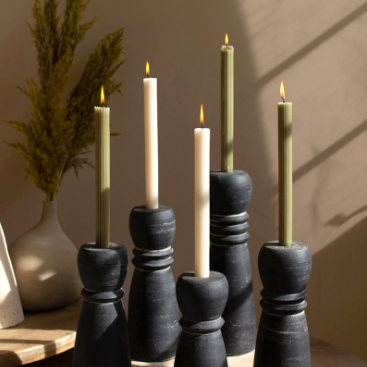 Set of black candle holders with lit candles on a wooden surface.