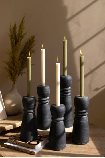 Set of black candle holders with lit candles on a wooden surface.
