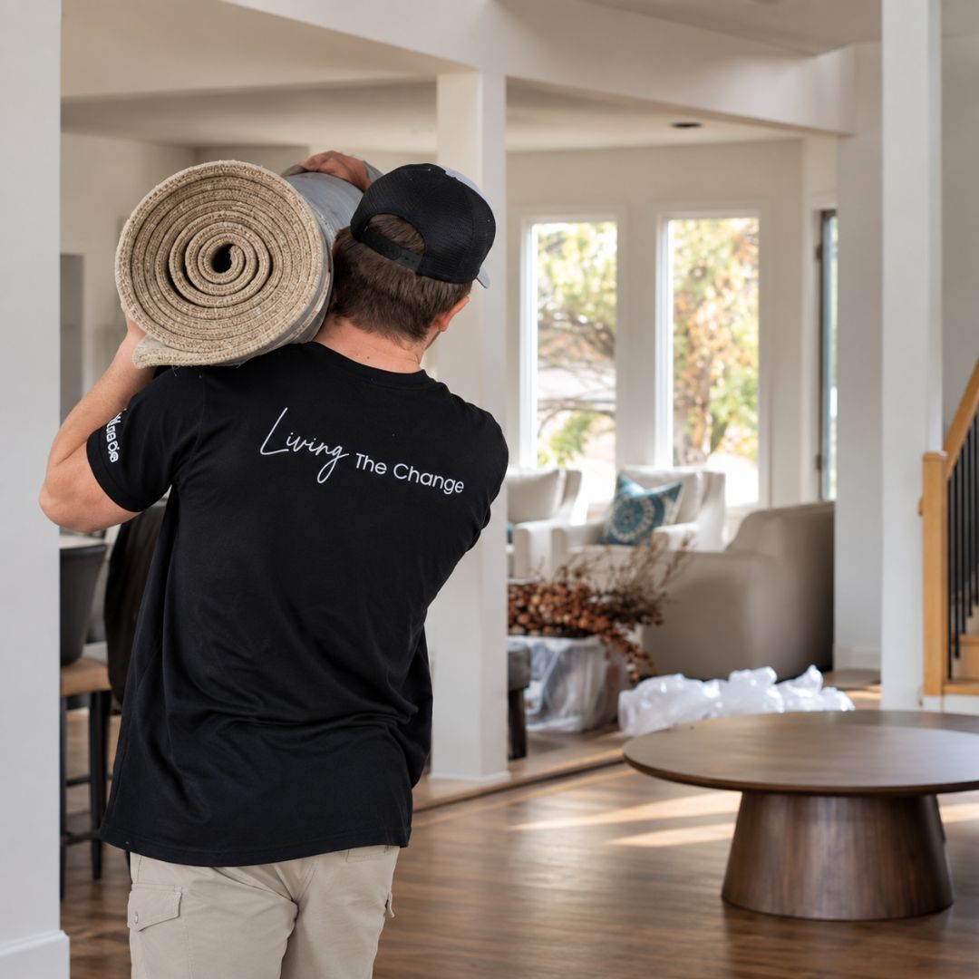 A Change Everything team member carries an area rug into a client’s home for professional placement.
