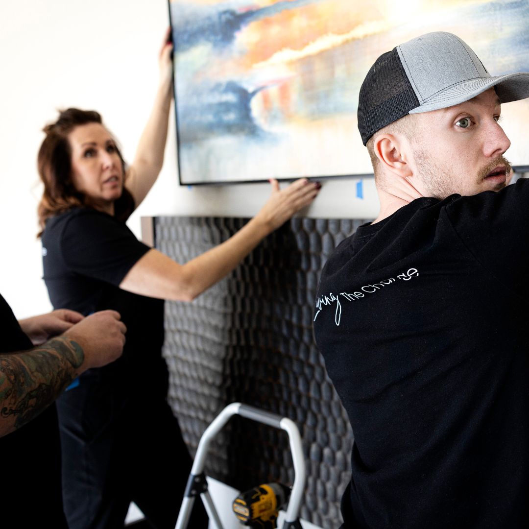 The Change Everything team places artwork above a fireplace during the final styling of a client’s home.
