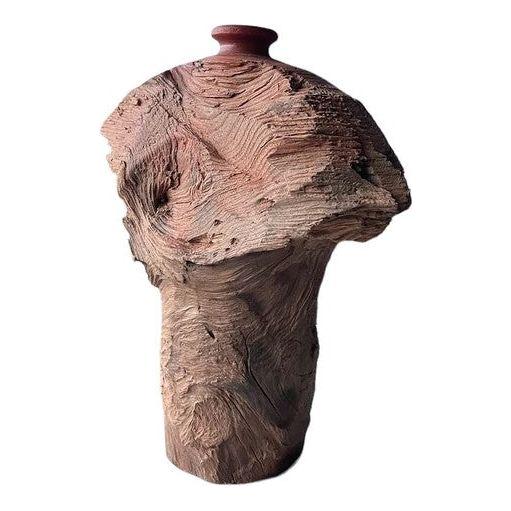 A rustic, textured ceramic Cloud Vase with a rough, bark-like surface. Hand-carved with an irregular, organic shape, it has a narrow base that widens asymmetrically towards the top. The earthy brown tones and intricate grooves evoke a weathered tree trunk, symbolizing growth and prosperity.