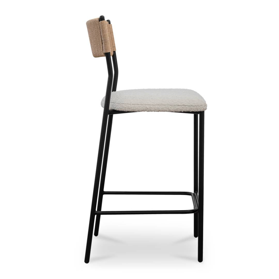 The Soren Performance Fabric Counter Stool features a slim black metal frame with a footrest, a textured beige performance fabric seat cushion, and a small woven paper rope back. Shown in profile against a white background.