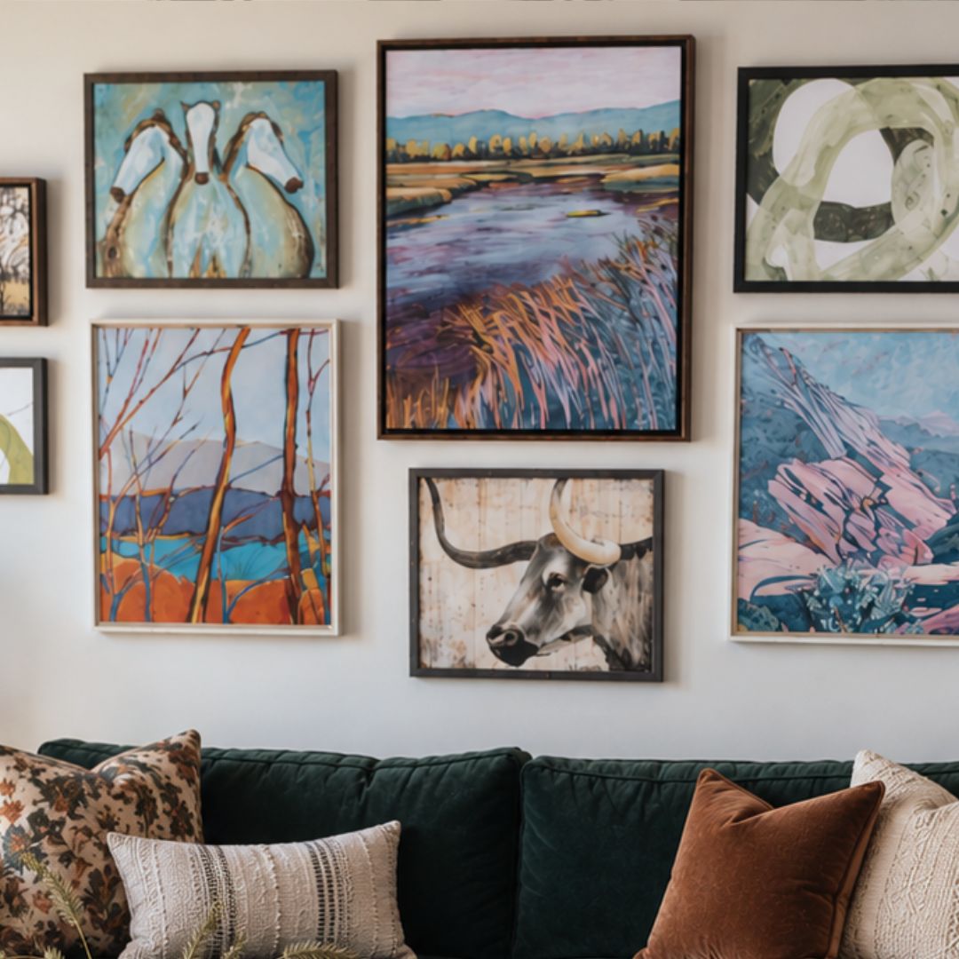 A gallery wall display of seven framed abstract and landscape paintings above a dark green velvet sofa with patterned throw pillows.