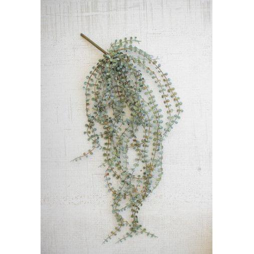 The Hanging Necklace Fern features a single artificial vine with small, round green leaves that cascade loosely from thin stems against a textured off-white background. Multiple delicate strands hang downward in various directions.