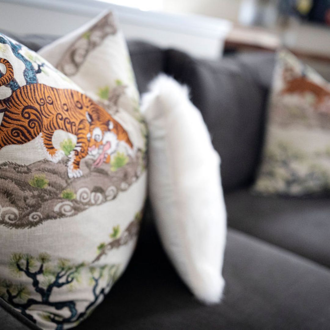 Patterned and textured throw pillows professionally layered on a charcoal sofa.