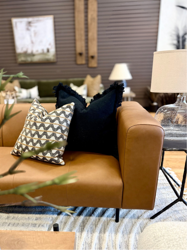 nomadic nest collection cognac leather sofa with a black and a black and white throw pillow.png
