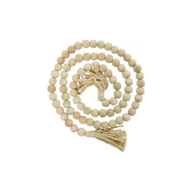 A Wood Beaded Garland, 80" long, is coiled in a circular pattern. The garland consists of uniformly sized round wooden beads. Each end of the garland is adorned with a tassel made of natural fibers, enhancing its rustic appearance. The tassels are tied securely with wrappings that match the fiber color.