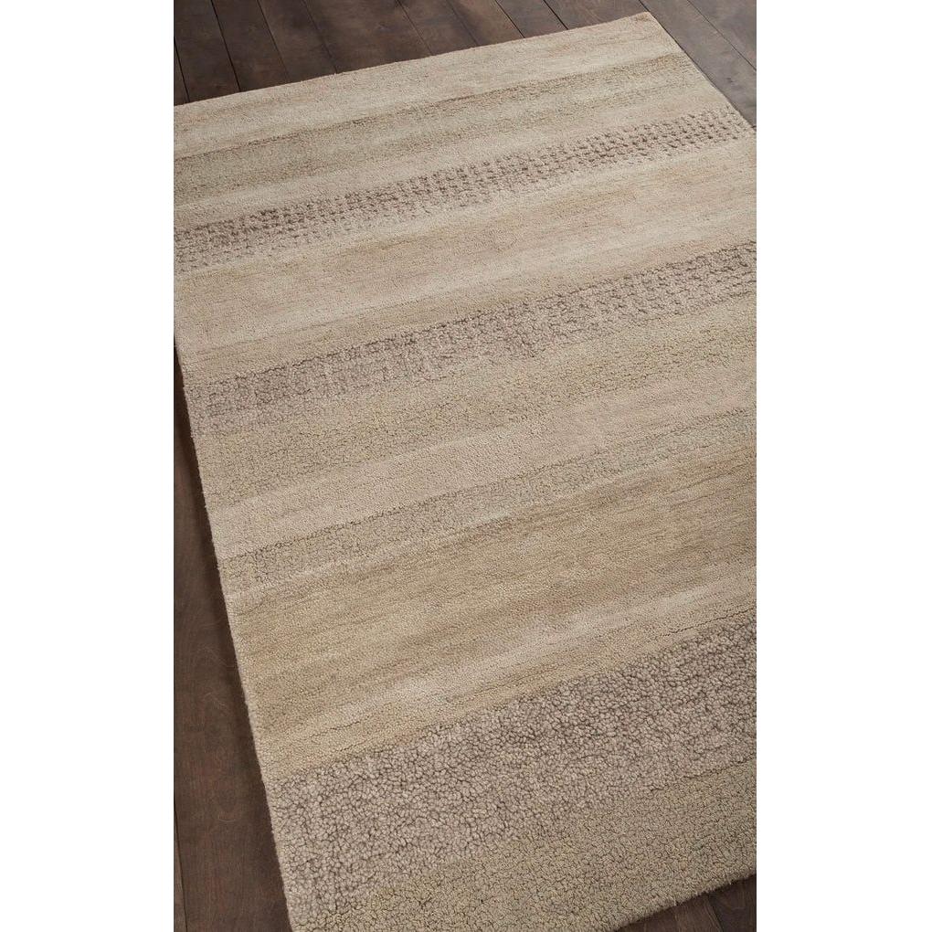 The Dejon Wool Rug, a rectangular beige area rug with textured horizontal stripes in tan and sand, sits on a dark wooden floor. Its minimal pattern and neutral tones create a natural, understated look.