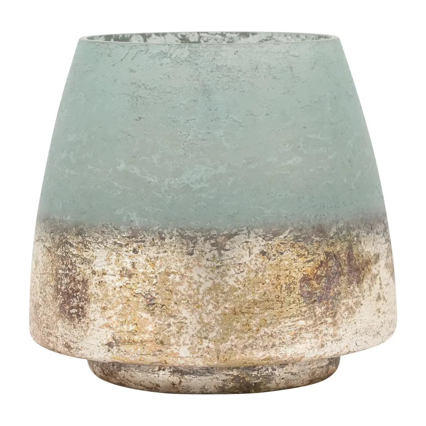 The Cambridge Hurricane Vase is a small, round vase with a wide base and tapered top. The top half is crafted from frosted seafoam green glass, while the lower half features an antiqued gold base with subtle patches of tarnish that blend the colors together. This versatile home decor piece boasts a worn and artisanal texture.