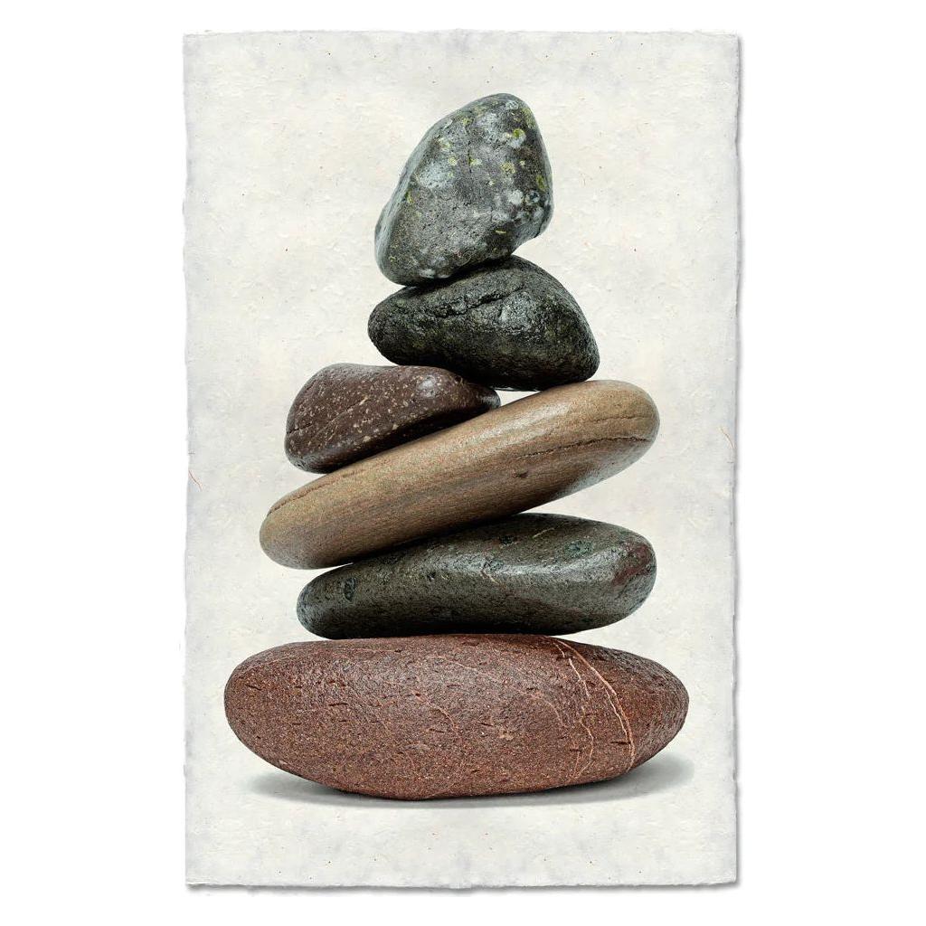 Balanced (3) features a stack of six smooth stones in dark gray, greenish, brown, and reddish tones, arranged from largest to smallest on a textured white background reminiscent of handmade Nepalese paper.
