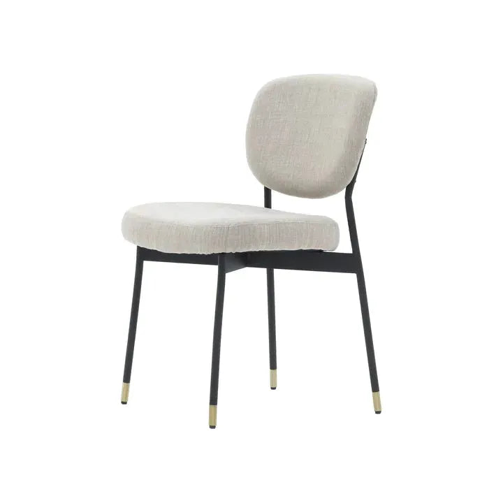 The Ridge Dining Chair is a minimalist masterpiece, showcasing a soft light gray cushioned backrest and seat atop an elegant black metal frame. Its design includes four slender legs finished with brass-colored caps, which stand out beautifully against a plain white backdrop, emphasizing its modern sophistication.