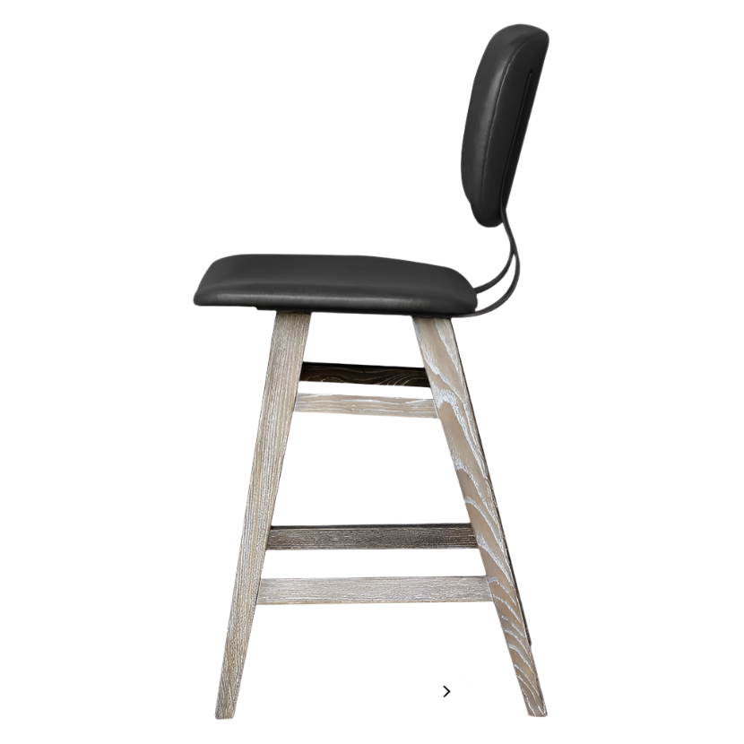 Side view of the Fraser Counter Stool, featuring a black cushioned seat and backrest. Its acacia wood structure with a natural finish highlights minimalist elegance, and an integrated footrest is within the leg support. The background is plain white.