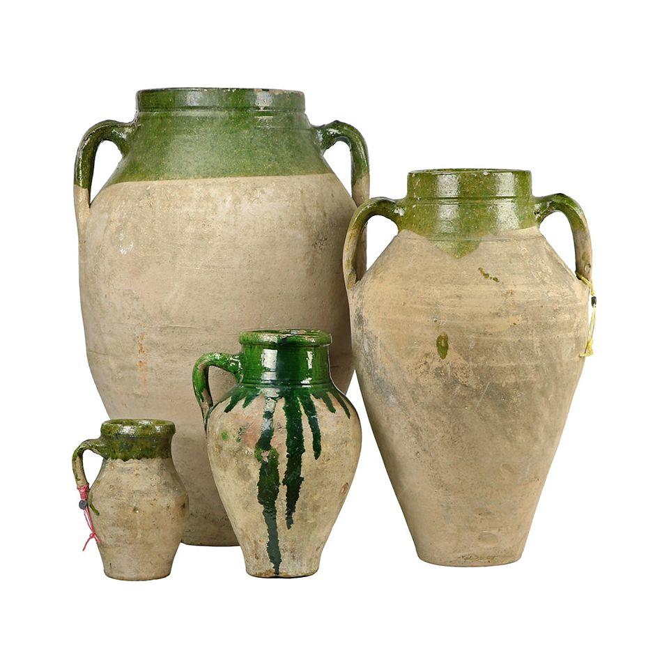 The Olive Jar set features four rustic ceramic jugs with dual handles, beige unglazed bases, and green glaze accents, reminiscent of Mediterranean style, displayed from tallest to smallest on a white background.