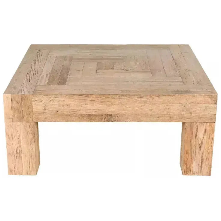 The Block Coffee Table, Natural, is a square wooden piece with a parquet-like top showcasing the rich grain of reclaimed oak. Its natural light finish and thick corner legs combine modern design with a strong, minimalist look.