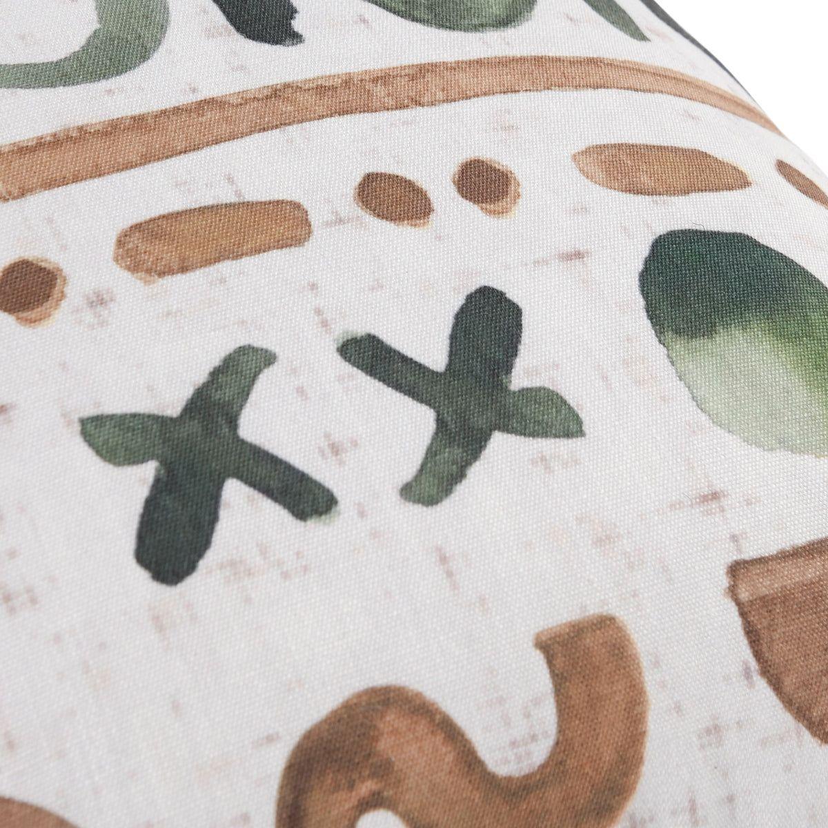 Close-up of the Indoor/Outdoor Monterey Natural/Green Throw Pillow's weather-resistant fabric, featuring hand-painted green X shapes, brown lines, and a green oval for a rustic, artistic look with faint speckles on its textured background.