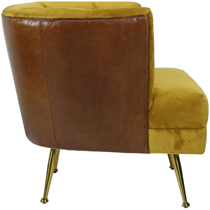 The Lobby Accent Chair features a mustard yellow velvet seat and leather back, with channel tufting and four angled gold metal legs for a stylish mid-century modern look. Side-rear view shown in image.